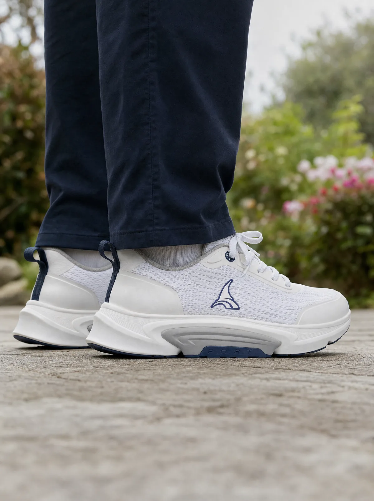 A senior standing at a low three-quarter angle. The outsole meets the ground wider than the foot above it.